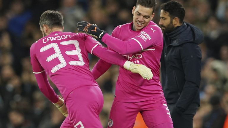 Manchester City's goalkeeper Scott Carson, left, replaces Manchester City's goalkeeper Ederson during the Champions League round of 16 second leg soccer match between Manchester City and Sporting Lisbon at the City of Manchester Stadium in Manchester, England, Wednesday, March 9, 2022. (AP Photo/Dave Thompson)