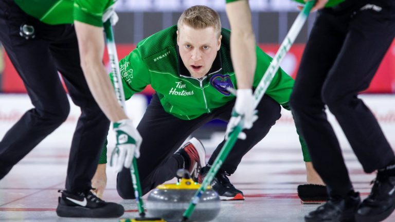 Team Saskatchewan skip Colton Flasch, centre, makes a shot as lead Daniel Marsh, left, and second Kevin Marsh sweep while playing Team Northern Ontario during playoff action at the Tim Hortons Brier in Lethbridge, Alta., Friday, March 11, 2022. (Jeff McIntosh/CP)