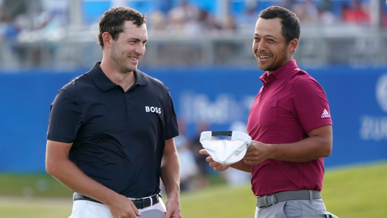 Patrick Cantlay laughs with teammate Xander Schauffele, right, on the 18th green after completing their third round of the PGA Zurich Classic golf tournament, Saturday, April 23, 2022, at TPC Louisiana in Avondale, La. (AP)