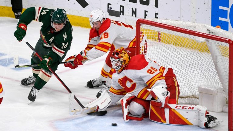 Minnesota Wild Joel Eriksson Ek, left, tries to get a shot past Calgary Flames goalie Jacob Markstrom (25) as Flames center Elias Lindholm, center, defends during the third period of an NHL hockey game Thursday, April 28, 2022, in St. Paul, Minn. The Wild won 3-2 in overtime. (Craig Lassig/AP Photo)