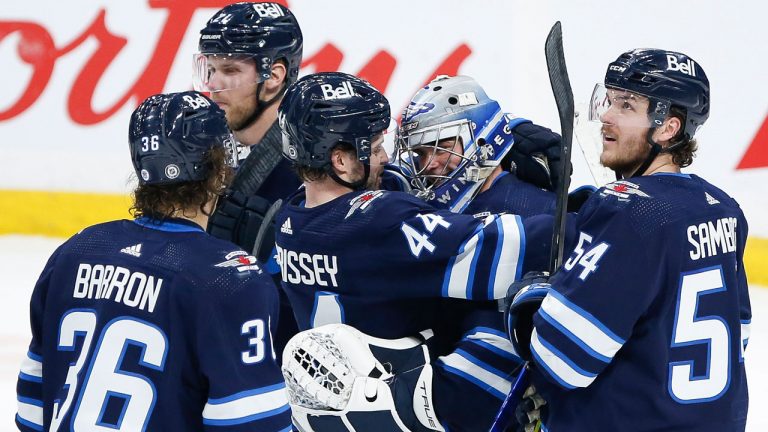 Winnipeg Jets' Josh Morrissey (44) congratulates goaltender Eric Comrie (1) for his first NHL shutout earned against the Philadelphia Flyers. (John Woods/CP)