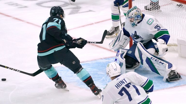 Vancouver Canucks goaltender Thatcher Demko, right, eyes the puck after making a stop of a shot by Seattle Kraken left wing Max McCormick (71) during the first period of an NHL hockey game Saturday, Jan. 1, 2022, in Seattle. (AP Photo/Ted S. Warren)