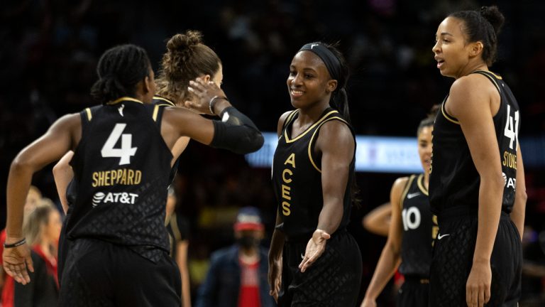 Las Vegas Aces guard Aisha Sheppard (4) slaps hands with guard Jackie Young, center, during the second half of a WNBA basketball game against the Phoenix Mercury Saturday, May 21, 2022, in Las Vegas. At right is Las Vegas Aces center Kiah Stokes (41). (AP Photo/Ellen Schmidt)
