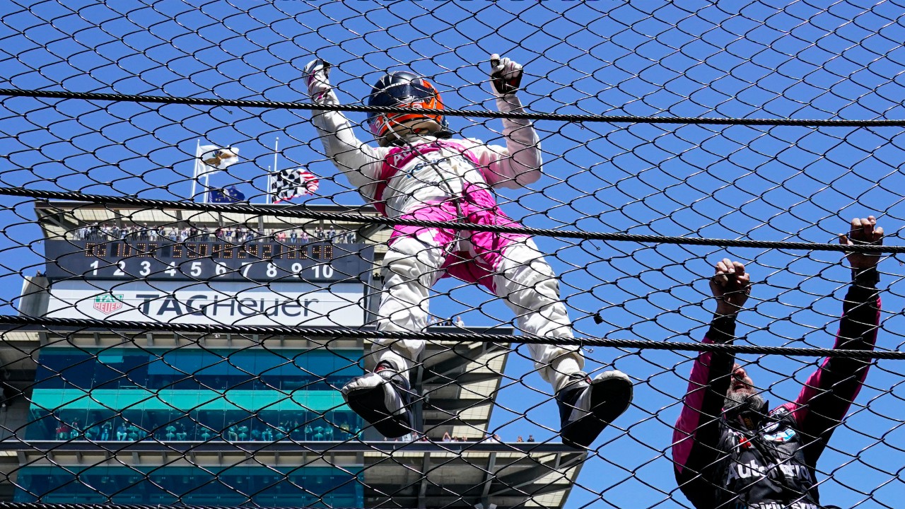 Helio Castroneves of Brazil climbs the fence at the start/finishing as he celebrates after winning the Indianapolis 500 auto race at Indianapolis Motor Speedway in Indianapolis, Monday, May 31, 2021. (Paul Sancya/AP)