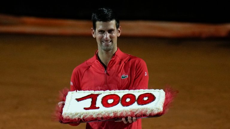 Serbia's Novak Djokovic holds a cake adorned with the number of his 1,000th tour-level win earned after winning his semifinal match against Norway's Casper Ruud at the Italian Open tennis tournament, in Rome, Saturday, May 14, 2022. (Alessandra Tarantino/AP)