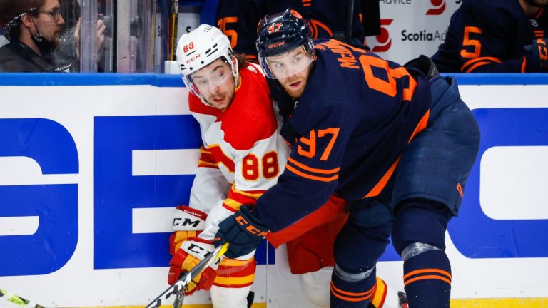 Calgary Flames forward Andrew Mangiapane, left, is checked by Edmonton Oilers centre Connor McDavid during first period NHL second round playoff hockey action in Edmonton, Sunday, May 22, 2022. (Jeff McIntosh/THE CANADIAN PRESS)