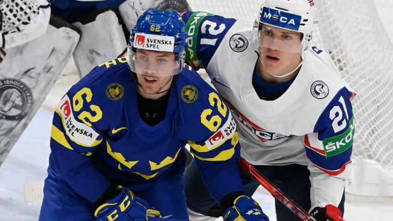 Sweden's Joel Kellman, left, and Norway's Christian Bull eye the puck during the 2022 IIHF World Hockey Championship preliminary round game in Tampere, Finland, on Sunday. (Jussi Nukari/AP)