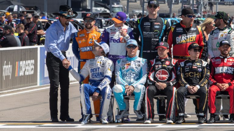 Richard Petty talks with NASCAR drivers, including Ryan Blaney, lower left, and Ricky Stenhouse Jr., upper left, before a group photo Friday, June 3, 2022, to promote the NASCAR Cup Series auto race at World Wide Technology Raceway in Madison, Ill. Petty won the Cup championship seven times. (Derik Holtmann/Belleville News-Democrat via AP)