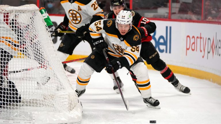 Boston Bruins defenceman Jack Ahcan (54) skates with the puck behind the net with Ottawa Senators left wing Alex Formenton (10) during second period NHL hockey action in Ottawa, on Saturday, Feb. 12, 2022. (Justin Tang/CP)