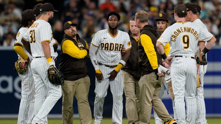 San Diego Padres left fielder Jurickson Profar, center, stands up briefly before falling over after colliding with shortstop C.J. Abrams during the fifth inning of a baseball game against the San Francisco Giants, Thursday, July 7, 2022, in San Diego. Profar and Abrams collided as Abrams made a catch for an out against Giants' Tommy La Stella. (Gregory Bull/AP)
