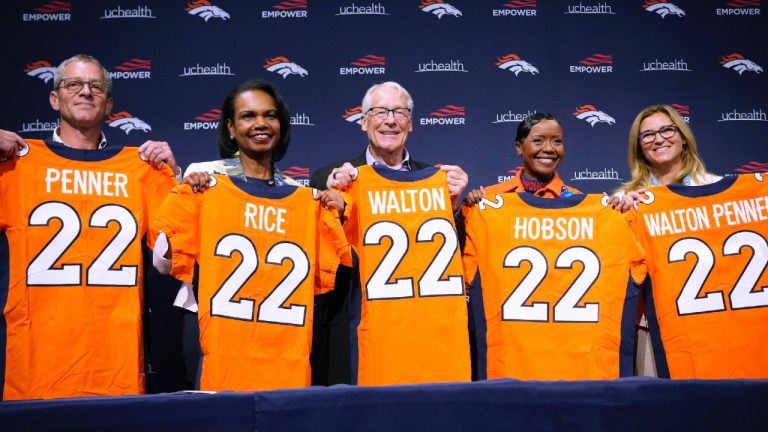 Gregory Penner, Condoleezza Rice, Rob Walton, Mellody Hobson and Carrie Walton Penner, from left, of the ownership group that purchased the Denver Broncos, pose with jerseys during a news conference at the NFL football team's headquarters Wednesday, Aug. 10, 2022, in Centennial, Colo. (David Zalubowski/AP)