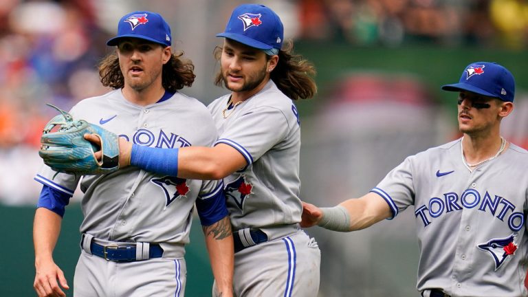 Toronto Blue Jays starting pitcher Kevin Gausman, left, is restrained by shortstop Bo Bichette, center, and second baseman Cavan Biggio after Gausman was called for a balk by second base umpire Jeff Nelson during the fourth inning of the first game of a baseball doubleheader against the Baltimore Orioles. (Julio Cortez/AP)