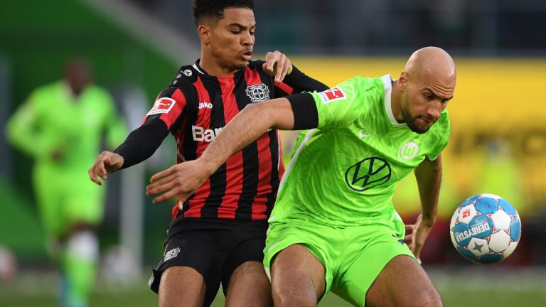 Wolfsburg's John Anthony Brooks, right, plays against Leverkusen's Amine Adli during the German Bundesliga soccer match between VfL Wolfsburg and Bayer Leverkusen at the Volkswagen Arena in Wolfsburg, Germany, Sunday, March 20, 2022. (Swen Pf'rtner/dpa via AP)