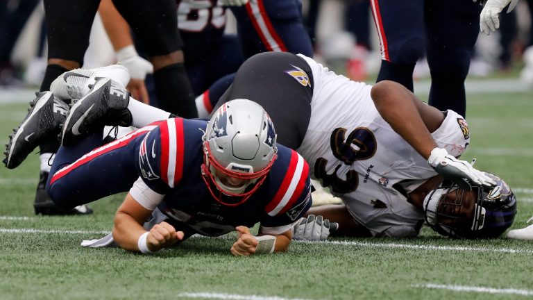 New England Patriots quarterback Mac Jones, left, is brought down by Baltimore Ravens defensive tackle Calais Campbell, right, in the second half of an NFL football game, Sunday, Sept. 25, 2022, in Foxborough, Mass. Jones limped to the sideline following the play. (Paul Connors/AP)