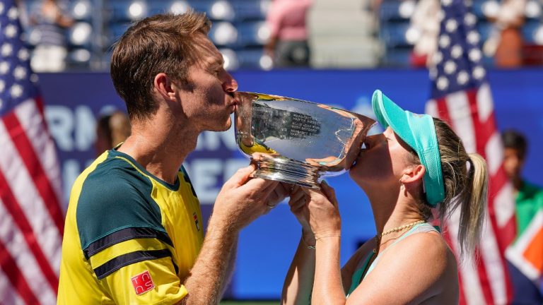 John Peers, left, and Storm Sanders, of Australia, kiss the championship trophy after winning the mixed doubles final against Kirsten Flipkens, of Belgium, and Edouard Roger-Vasselin, of France, at the U.S. Open tennis championships, Saturday, Sept. 10, 2022, in New York. (Matt Rourke/AP)