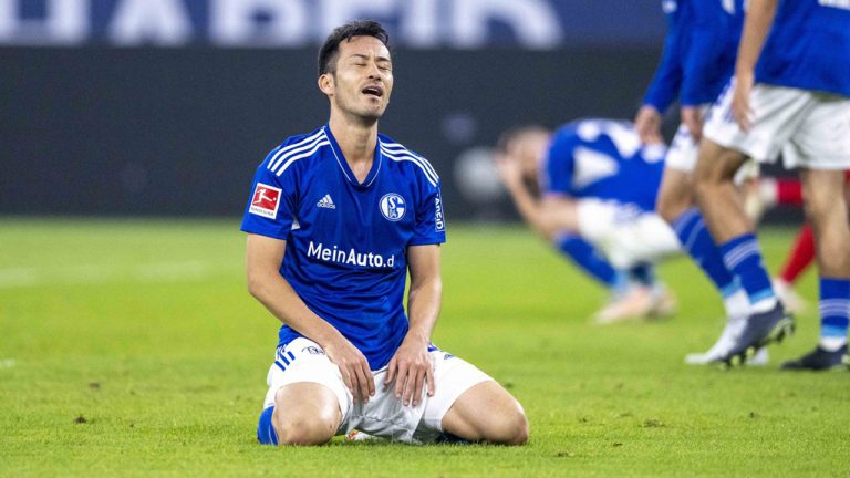 Schalke's Maya Yoshida sits on the pitch after scoring to 2-3 during the German Bundesliga soccer match between Schalke 04 and FC Augsburg at the Veltins Arena in Gelsenkirchen, Germany, Sunday Oct. 2, 2022. (David Inderlied/dpa via AP)