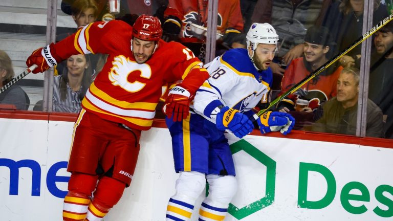 Buffalo Sabres forward Zemgus Girgensons, right, is checked by Calgary Flames forward Milan Lucic during first period NHL hockey action in Calgary, Thursday, Oct. 20, 2022. (Jeff McIntosh/THE CANADIAN PRESS)