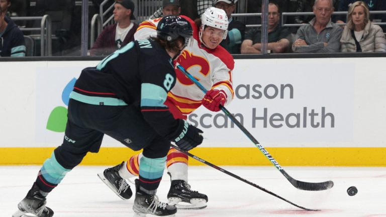 Calgary Flames forward Sonny Milano, right, passes the puck under pressure from Seattle Kraken defenseman Cale Fleury during the third period of a preseason NHL hockey game Tuesday, Sept. 27, 2022, in Seattle. (Jason Redmond/AP) 