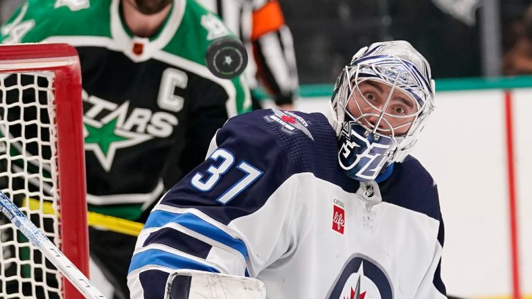 The puck defects off of Winnipeg Jets goaltender Connor Hellebuyck (37) as Dallas Stars left wing Jamie Benn (14) looks on during the first period of an NHL hockey game in Dallas, Friday, Nov. 25, 2022. (LM Otero/AP)