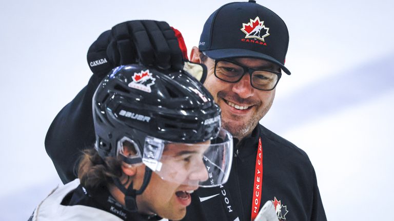 Dennis Williams pats defenceman Daemon Hunt on the helmet during a training camp practice in Calgary on Tuesday, Aug. 2, 2022 (Jeff McIntosh/CP)