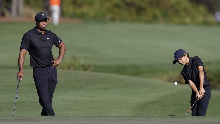 Tiger Woods, left, watchs his son Charlie chip onto the fifth green during the first round of the PNC Championship golf tournament Friday, Dec. 17, 2021, in Orlando, Fla. (Scott Audette/AP)
