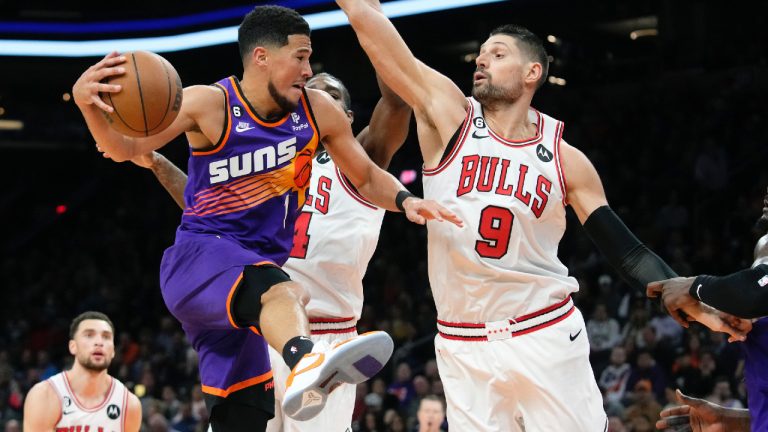 Phoenix Suns guard Devin Booker (1) is stopped on a drive to the basket by Chicago Bulls center Nikola Vucevic (9) and Bulls forward Patrick Williams, second from right, as Bulls guard Zach LaVine, left, looks on during the first half of an NBA basketball game in Phoenix, Wednesday, Nov. 30, 2022. (Ross D. Franklin/AP)