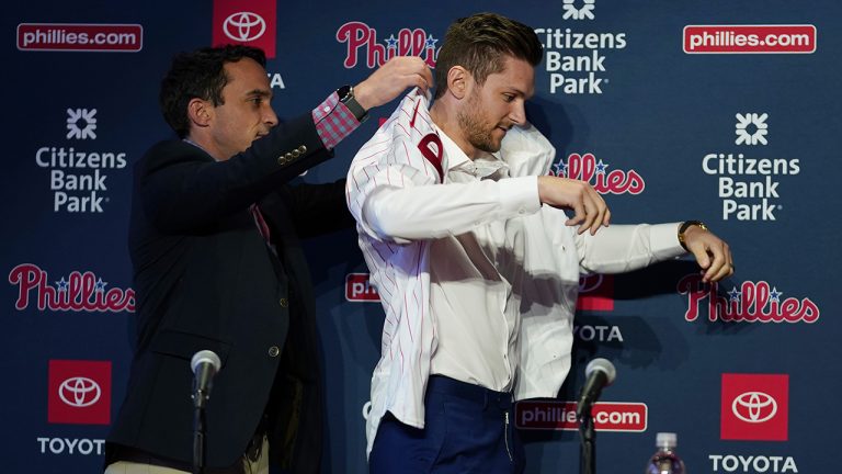 Philadelphia Phillies general manager Sam Fuld, left, helps newly-aquired shortstop Trea Turner with his jersey during his introductory news conference, Thursday, Dec. 8, 2022, in Philadelphia. (Matt Slocum/AP)