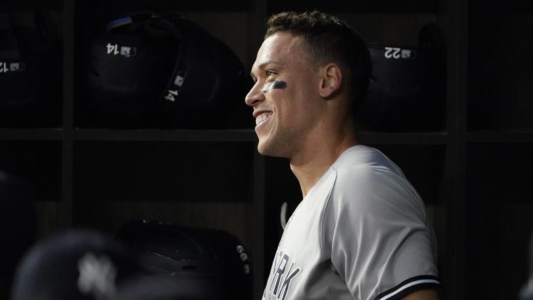 New York Yankees' Aaron Judge smiles in the dugout after hitting a solo home run, his 62nd of the season, during the first inning in the second baseball game of a doubleheader against the Texas Rangers in Arlington, Texas, Tuesday, Oct. 4, 2022. With the home run, Judge set the AL record for home runs in a season, passing Roger Maris. (LM Otero/AP)