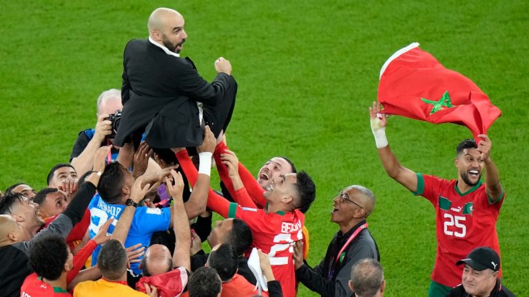 Morocco players celebrate with Morocco's head coach Walid Regragui at the end of the World Cup quarterfinal soccer match between Morocco and Portugal, at Al Thumama Stadium in Doha, Qatar, Saturday, Dec. 10, 2022. (Luca Bruno/AP Photo)