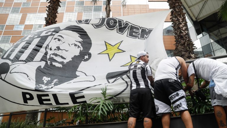 Santos soccer team supporters secure a banner with the image of former soccer star Pele, in front of the Albert Einstein hospital where he is hospitalized in Sao Paulo. (Marcelo Chello/AP)