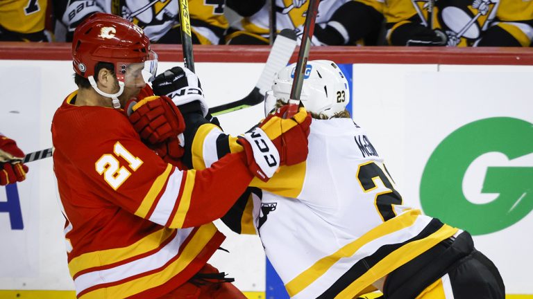 Pittsburgh Penguins forward Brock McGinn, right, checks Calgary Flames forward Kevin Rooney during second period NHL hockey action in Calgary, Tuesday, Oct. 25, 2022. (Jeff McIntosh/CP)