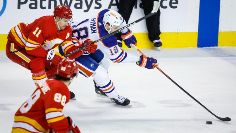 Edmonton Oilers forward Zach Hyman, right, steals the puck from Calgary Flames forward Mikael Backlund during first period NHL hockey action in Calgary, Tuesday, Dec. 27, 2022.(Jeff McIntosh/CP)