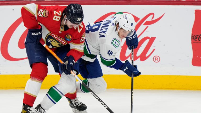 Florida Panthers defenseman Josh Mahura (28) and Vancouver Canucks center Jack Studnicka (18) battle for the puck during the second period of an NHL hockey game, Saturday, Jan. 14, 2023, in Sunrise, Fla. (AP Photo/Wilfredo Lee)