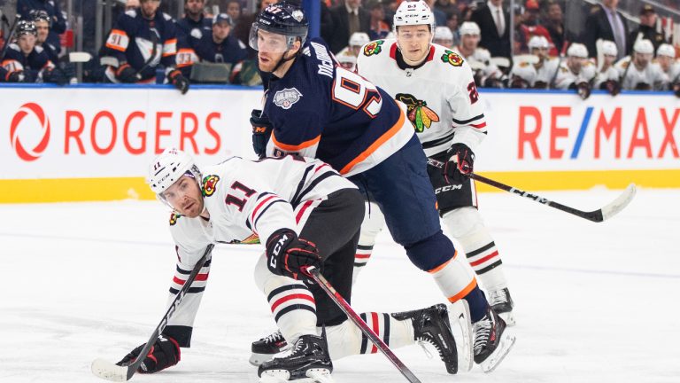 Chicago Blackhawks' Taylor Raddysh (11) and Edmonton Oilers' Connor McDavid (97) battle for the puck during first period NHL action in Edmonton on Saturday January 28, 2023. (Jason Franson/CP)