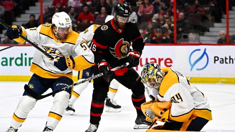 The puck bounces in the glove of Nashville Predators goaltender Juuse Saros (74) as he makes a save in front of Ottawa Senators left wing Austin Watson (16) and Nashville Predators defenceman Dante Fabbro (57), during second period NHL hockey action in Ottawa, on Monday, Jan. 9, 2023. Justin Tang/THE CANADIAN PRESS