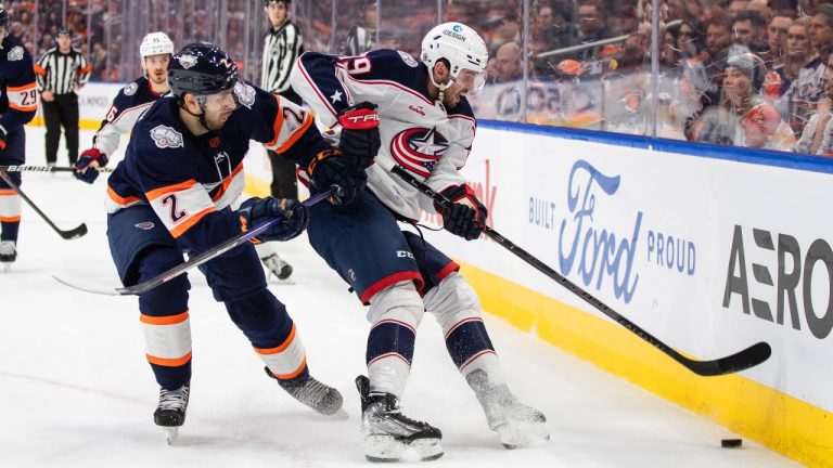 Columbus Blue Jackets' Liam Foudy (19) and Edmonton Oilers' Evan Bouchard (2) battle for the puck during first period NHL action in Edmonton on Wednesday January 25, 2023. (Jason Franson/THE CANADIAN PRESS)