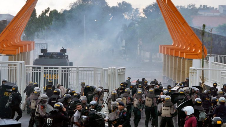 Riot police officers fire tear gas to disperse soccer supporters outside Jatidiri Stadium in Semarang, Central Java, Indonesia, Friday, Feb. 17, 2023. Indonesian police fired tear gas to disperse fans who were trying to force their way into a match that was held without spectators, months after the use of tear gas in another stadium in East Java caused one of the world's worst sporting disasters. (AP Photo/Adhik Kurniawan)