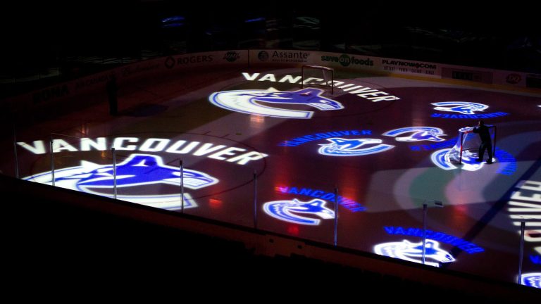 A worker moves a hockey net as Vancouver Canucks team logos are projected on the ice before the team's NHL hockey game against the Detroit Red Wings in Vancouver, B.C., on Thursday February 2, 2012. (Darryl Dyck/CP)