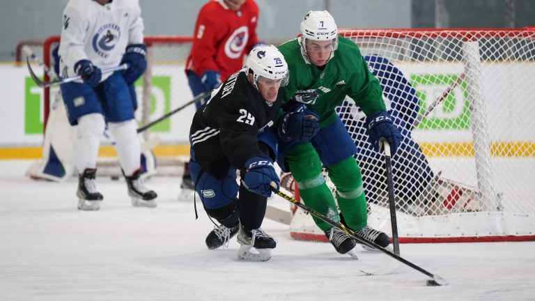 Vancouver Canucks' Kirill Kudryavtsev (29) reaches for the puck while being checked by William Lockwood (7) during the NHL hockey team's training camp in Whistler, B.C., Thursday, Sept. 22, 2022. (Darryl Dyck/CP)