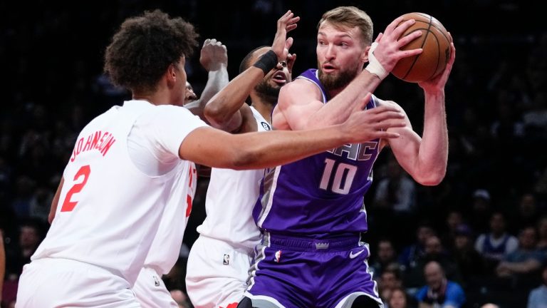 Sacramento Kings' Domantas Sabonis (10) protects the ball from Brooklyn Nets' Cameron Johnson (2) and Mikal Bridges during the first half of an NBA basketball game Thursday, March 16, 2023, in New York. (Frank Franklin II/AP)