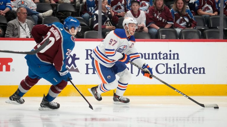 Edmonton Oilers center Connor McDavid, right, collects the puck as Colorado Avalanche center Nathan MacKinnon defends in the second period of an NHL hockey game Tuesday, April 11, 2023, in Denver. (David Zalubowski/AP)