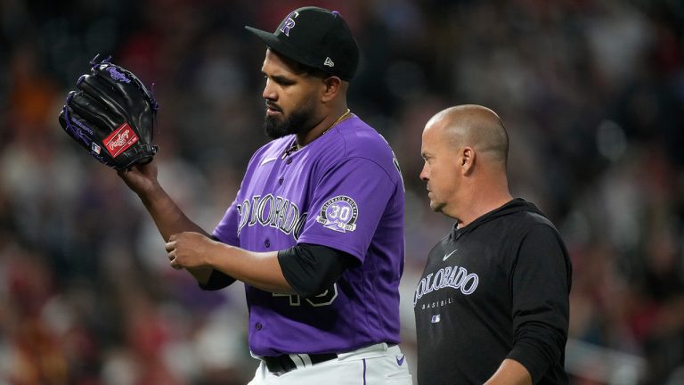Colorado Rockies starting pitcher German Marquez, left, holds up his throwing arm as he leaves the mound with assistant trainer Heath Townsend before the sixth inning of a baseball game against the St. Louis Cardinals, Monday, April 10, 2023, in Denver. (David Zalubowski/AP)