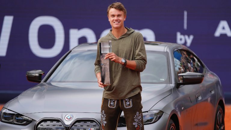 Holger Rune of Denmark poses with the trophy and the BMW i4 winner car after the final match against Botic Van De Zandschulp of the Netherlands at the Tennis ATP tournament in Munich, Germany, Sunday, April 23, 2023. (Matthias Schrader/AP)
