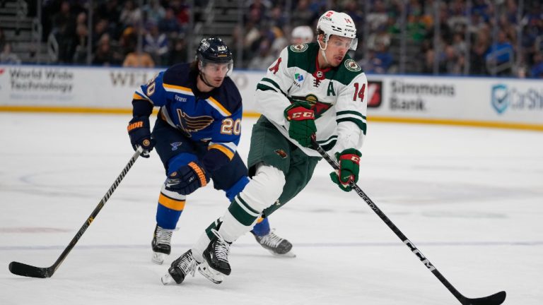 Minnesota Wild's Joel Eriksson Ek (14) brings the puck down the ice as St. Louis Blues' Brandon Saad (20) defends during the first period of an NHL hockey game Wednesday, March 15, 2023, in St. Louis. (Jeff Roberson/AP)
