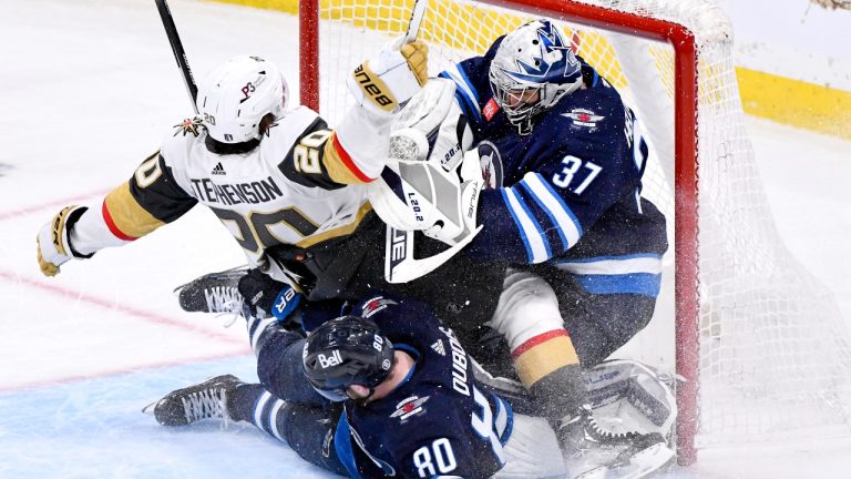 Vegas Golden Knights' Chandler Stephenson (20) collides with Winnipeg Jets goaltender Connor Hellebuyck (37) as he is pushed into the net by Pierre-Luc Dubois (80) during third period game 4 NHL Stanley Cup first round hockey playoff action in Winnipeg, Monday, April 24, 2023. (Fred Greenslade/THE CANADIAN PRESS)