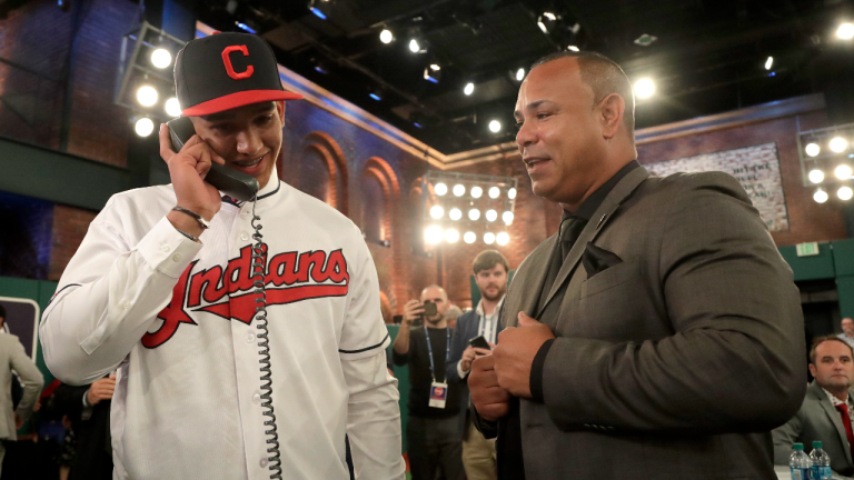 Former Cleveland Indians second baseman Carlos Baerga, right, watches as Daniel Espino, left, a right-handed pitcher from Georgia Premier Academy in Statesboro, Ga., speaks to Indians personnel over the phone after they selected Espino No. 24 in the first round of the Major League Baseball draft, Monday, June 3, 2019, in Secaucus, N.J. (AP)