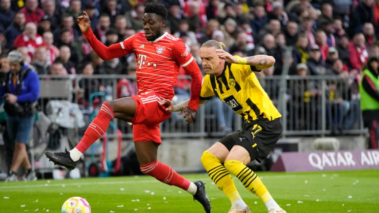 Bayern's Alphonso Davies, left, is challenged by Dortmund's Marius Wolf during the German Bundesliga soccer match between FC Bayern Munich and Borussia Dortmund at the Allianz Arena stadium in Munich, Germany, Saturday April 1, 2023. (Matthias Schrader/AP)