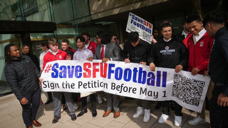 Simon Fraser University football team players hold a banner after attending a hearing at B.C. Supreme Court. (Darryl Dyck/THE CANADIAN PRESS)