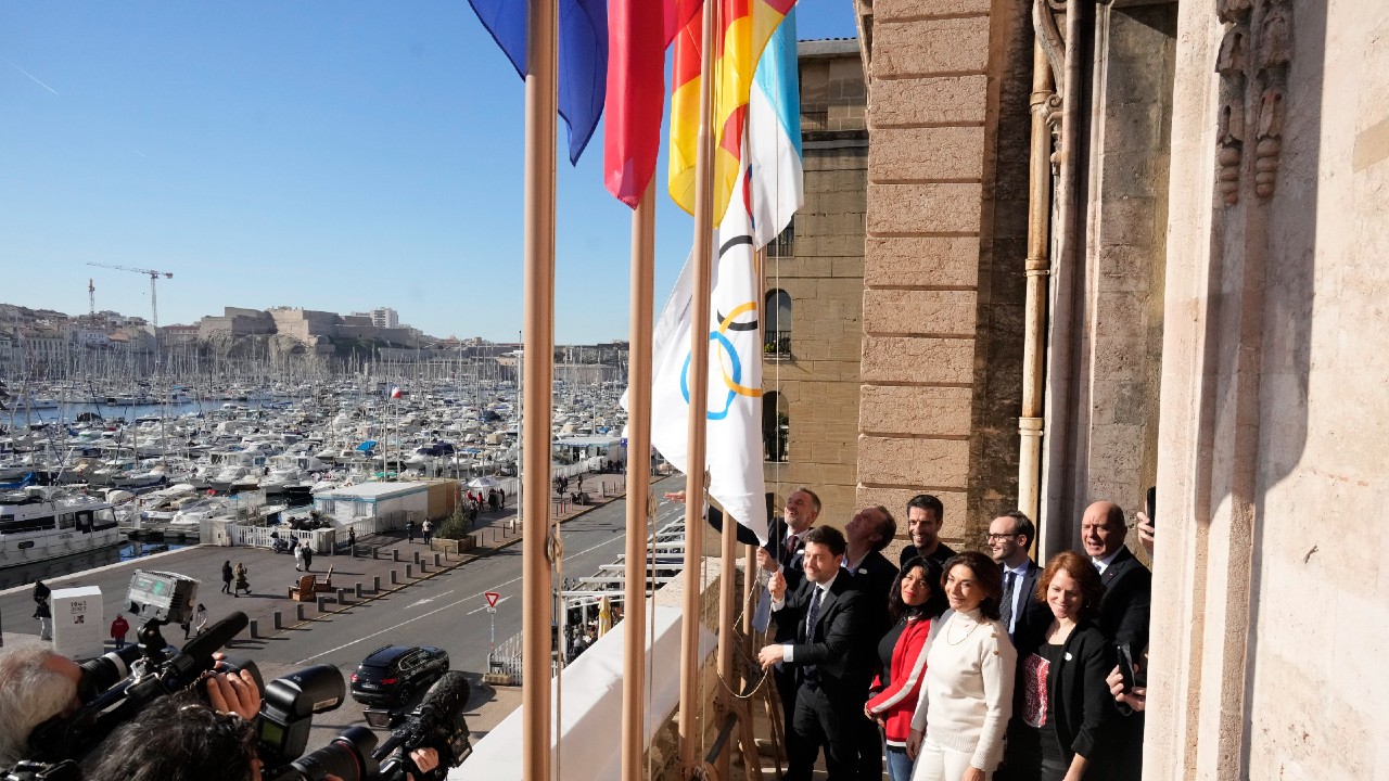 Mayor of Marseille Benoit Payan, left, raises the Olympic flag with Head of Paris 2024 Olympics Tony Estanguet, center, after a press conference at Marseille City Hall, southern France, Friday, Feb. 3. 2023. Instead of arriving overland, the symbolic flame alighting the Paris 2024 Games will take to the seas from its birthplace in Greece, arriving aboard a three-masted tall ship in the French port of Marseille. (AP Photo/Thibault Camus)