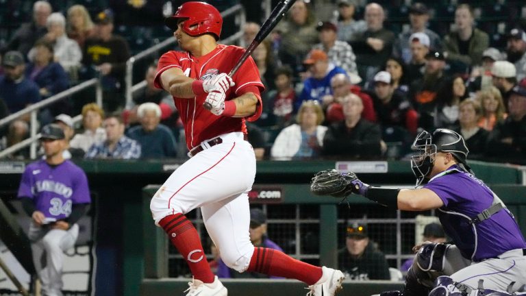 Cincinnati Reds' Christian Encarnacion-Strand, left, follows through on a swing on his infield single as Colorado Rockies catcher Brian Serven, right, looks on during the second inning of a spring training baseball game, Monday, March 6, 2023, in Goodyear, Ariz. (Ross D. Franklin/AP)